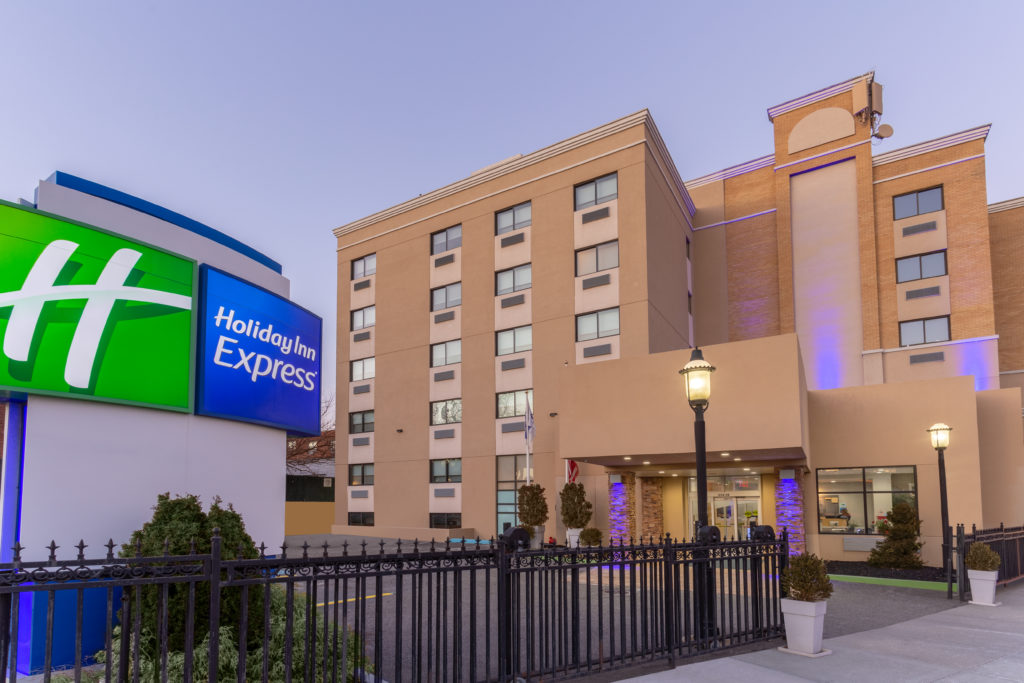 Holiday Inn Express LaGuardia Airport exterior with sign in evening